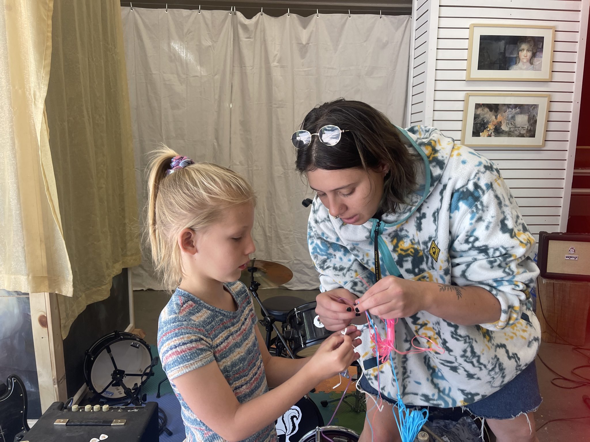 A teacher and a girl working together to untangle colorful cords in a music room